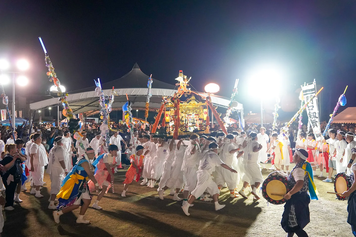 Portable shrine carried at night among decorated poles at Yamada Matsuri