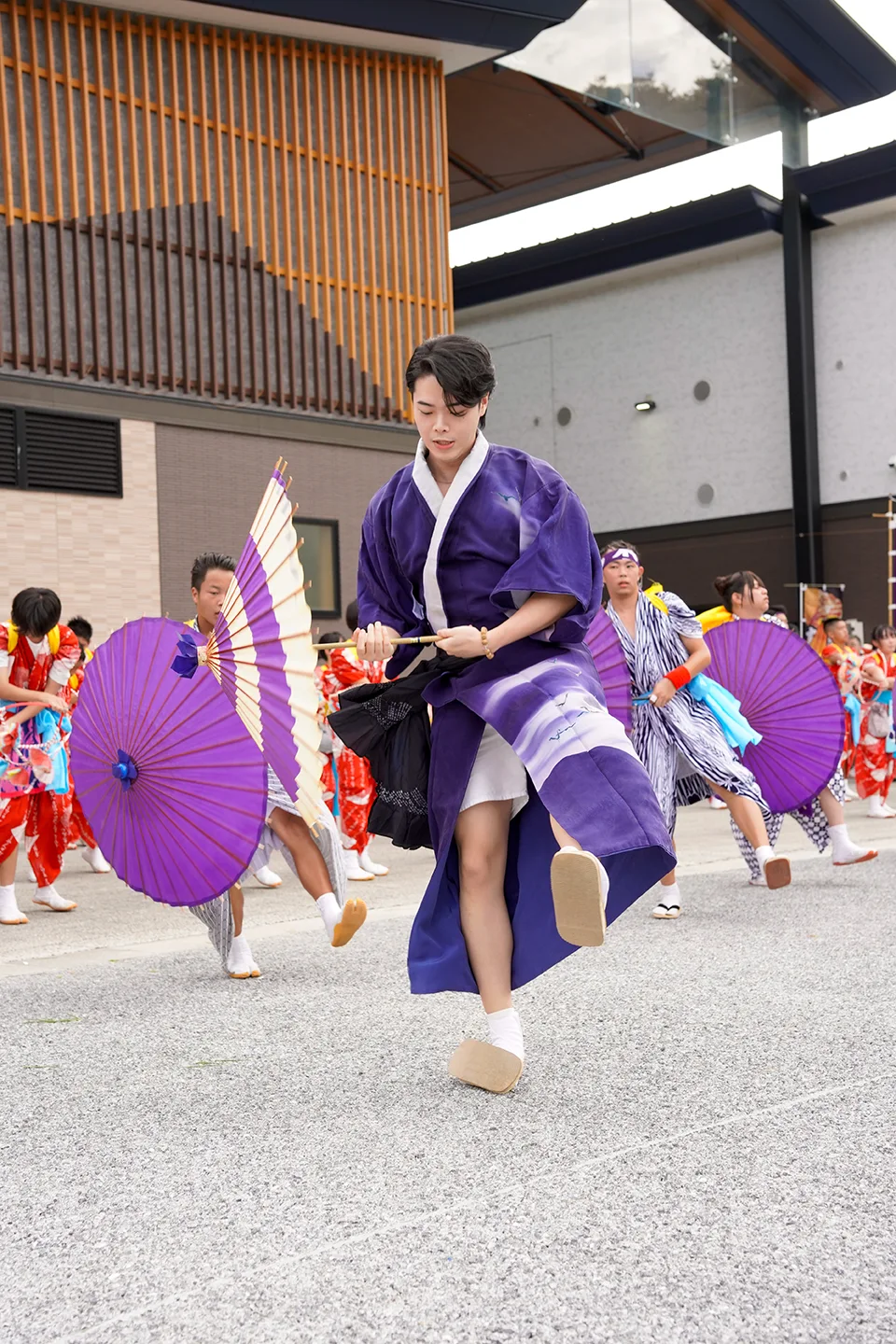 Dancers in purple costumes performing with paper umbrellas at Yamada Matsuri