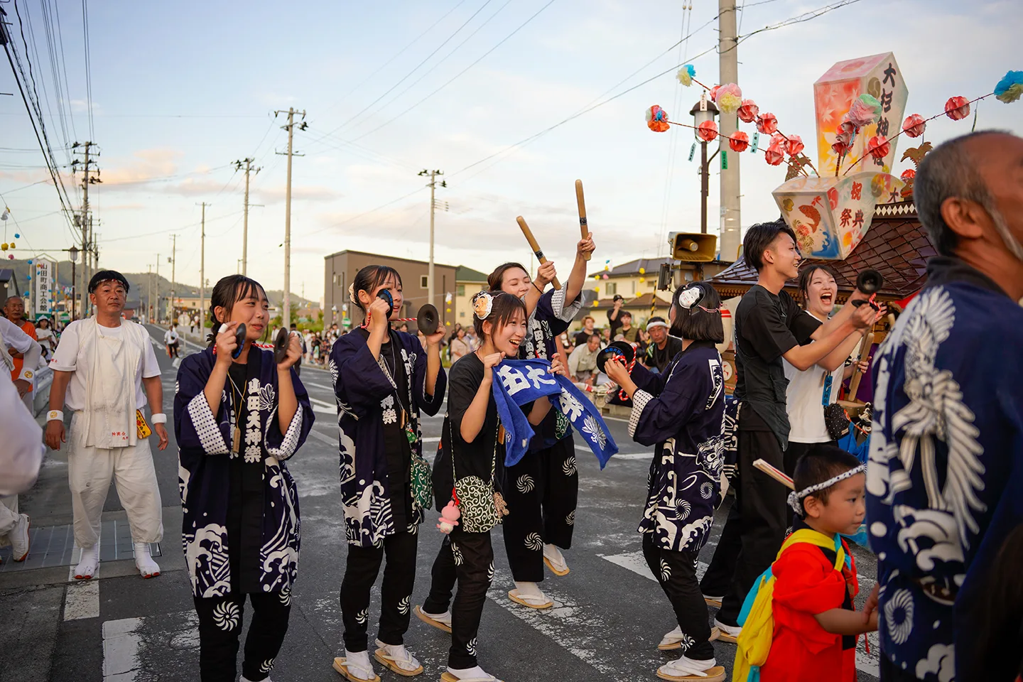 Women of Yamada Daikagura in happi coats striking hand gongs at Yamada Matsuri