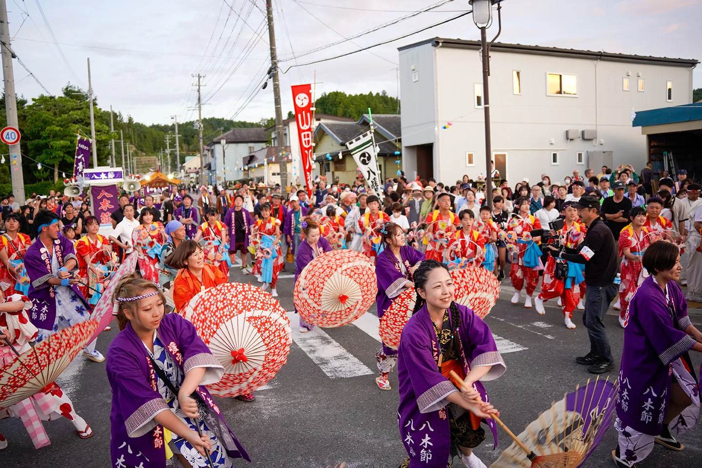 Yagi-bushi dancers twirling paper umbrellas at dusk during Yamada Matsuri