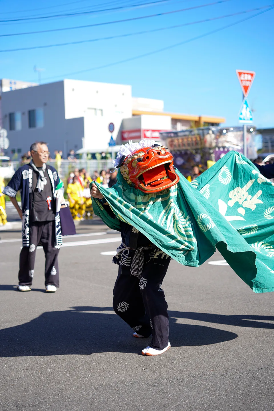 Lion dancer swirling a green body cloth on the street at Yamada Matsuri