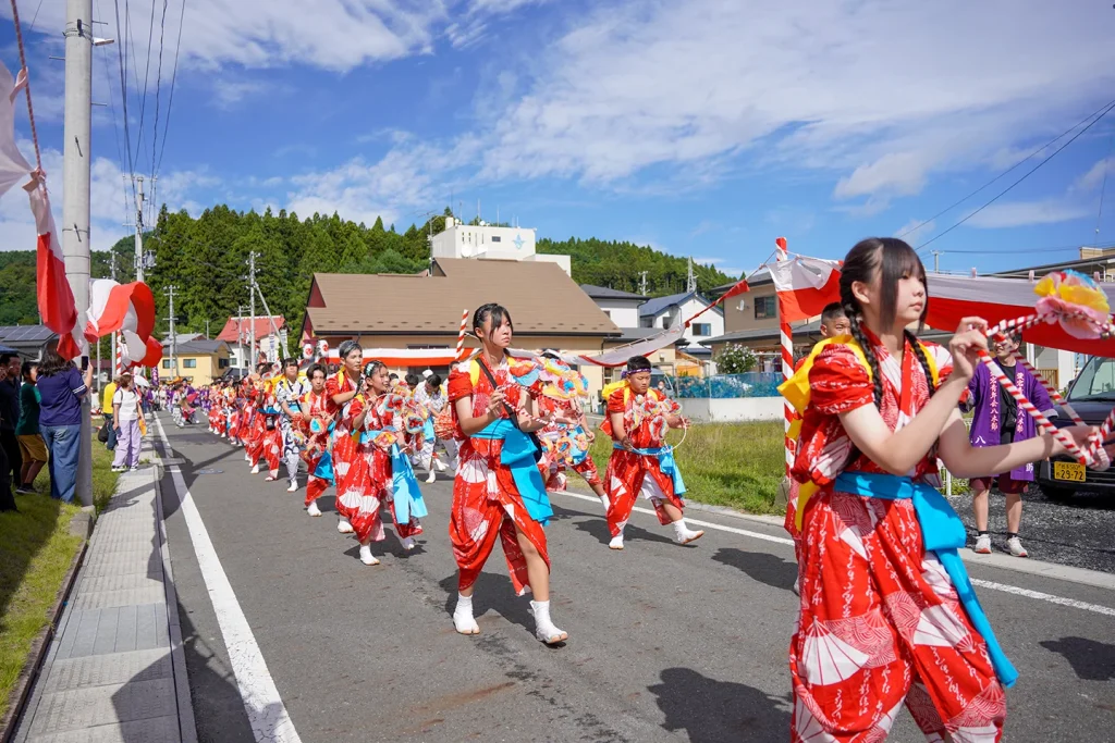 Children in red costumes dancing in a parade along the street at Yamada Matsuri