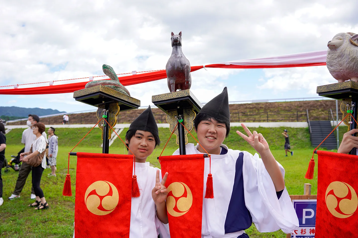 Boys in eboshi hats of Osugi Shrine standing before zodiac animal figures at Yamada Matsuri