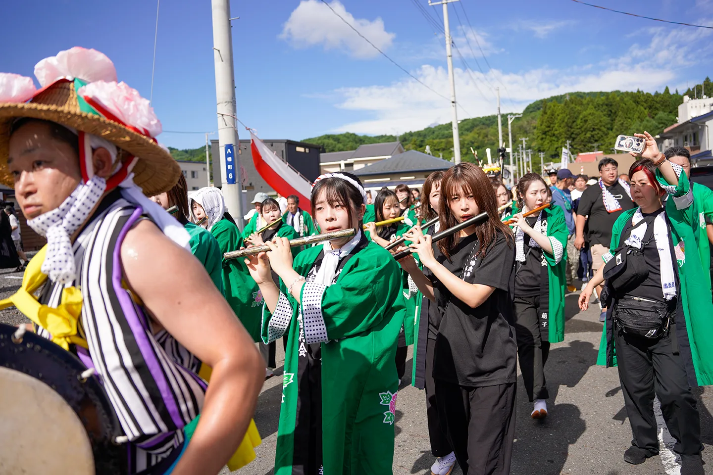 Flute players in green happi coats leading a parade at Yamada Matsuri