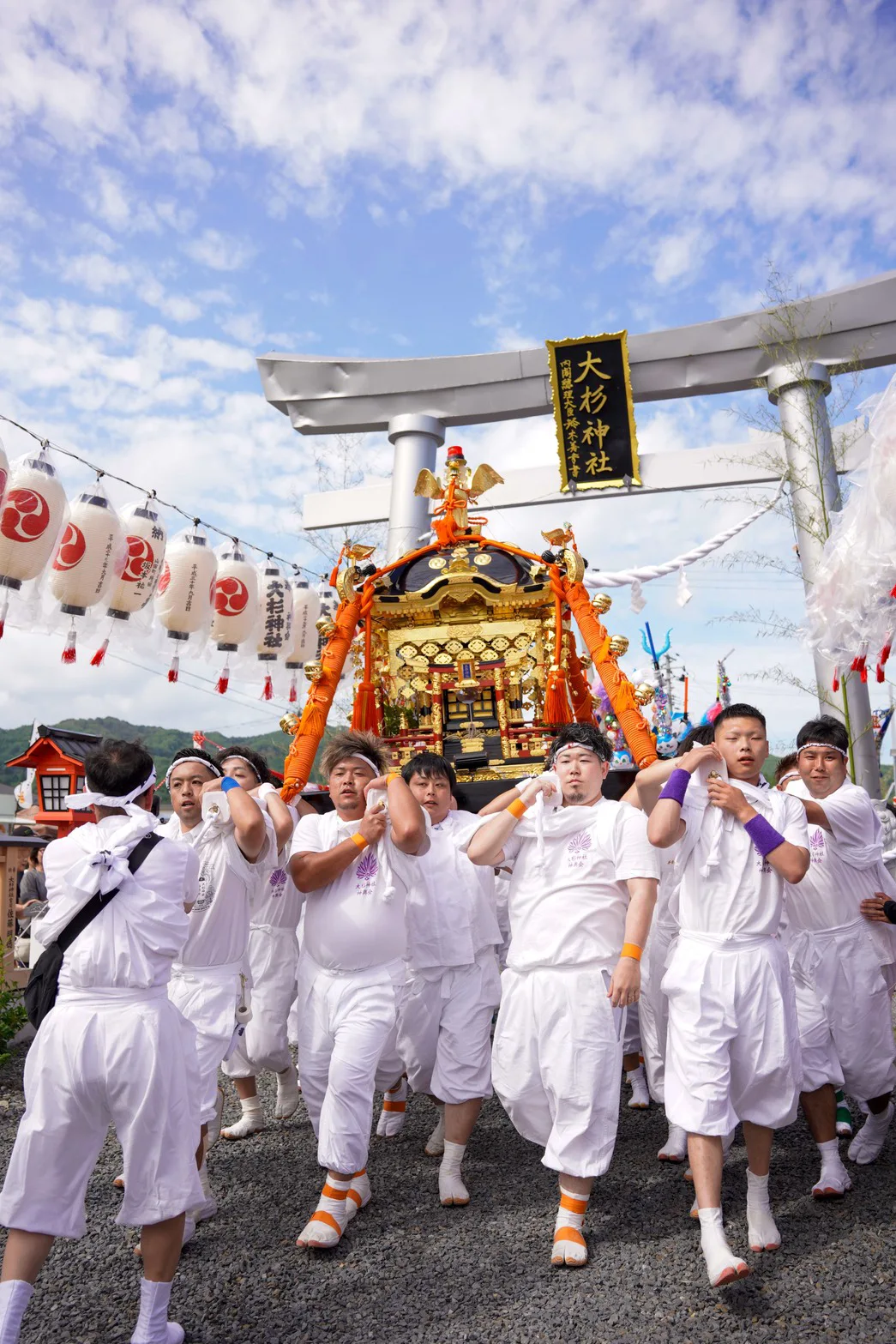 White-clad bearers carrying a golden portable shrine through the torii gate of Osugi Shrine at Yamada Matsuri